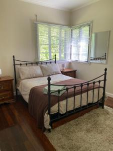 1 dormitorio con cama, espejo y ventanas en Coochin Cottage, Beerwah en Beerwah