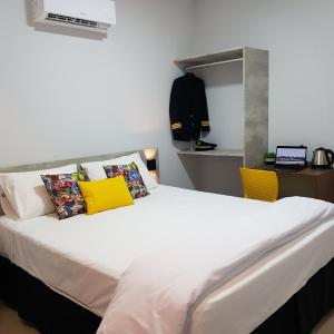 1 dormitorio con 1 cama blanca grande con almohadas amarillas en Aero Inn Hotel en Uberlândia