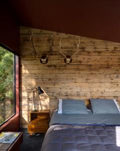 a bedroom with a wooden wall with a bed at Blackpool House in Oneroa