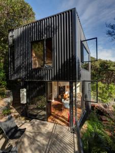 a black house with glass doors and a deck at Blackpool House in Oneroa