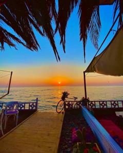 a sunset over the ocean with a bike on a dock at Happy Land Hotel Dahab in Dahab