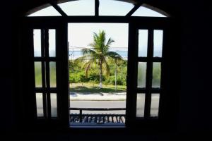 an open window with a view of a palm tree at Apto Frente para o Mar in Pontal do Paraná