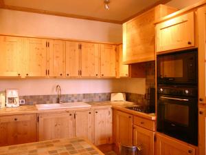 a kitchen with wooden cabinets and a black appliance at Appartement Les Deux Alpes, 5 pièces, 8 personnes - FR-1-348-173 in Les Deux Alpes