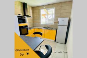 eine Küche mit gelben Schränken, einem Tisch und einem Kühlschrank in der Unterkunft Villa Auya entre mer et montagne in Le Carbet