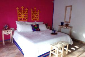- une chambre avec un grand lit blanc et un mur rouge dans l'établissement Villa Puerta Azul at La Casa de Frida, à Loreto