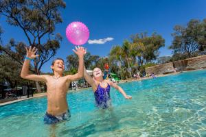 
a man and a boy playing frisbee in a pool at BIG4 Renmark Riverfront Holiday Park in Renmark
