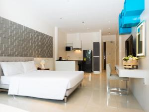 a bedroom with a large white bed and a kitchen at City Park Hotel Residences in Manila
