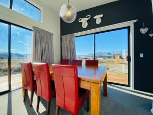 a dining room with a wooden table and red chairs at Flat White in Lake Tekapo