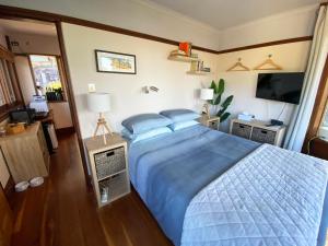 新月岬The Pool House - Crescent Head - stunning ocean views, pet friendly的一间卧室配有一张带蓝色床单的床和电视。
