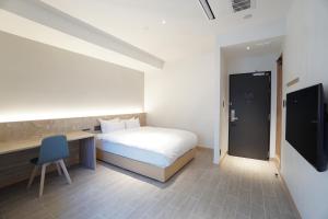 a bedroom with a bed and a desk and a television at THIRD ishigakijima in Ishigaki Island