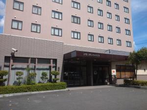 a large pink building with a parking lot in front of it at Iga Ueno City Hotel in Iga