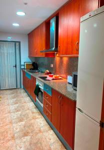 Una cocina con gabinetes de madera y un refrigerador blanco. en Ground Floor With Private Terrace And Community Area, Platanera, en Calafell