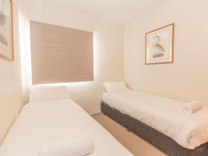 Duas camas num pequeno quarto com paredes brancas em The Nook 1 of5 The Nook em Jindabyne