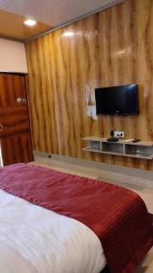 a bedroom with a bed and a tv on a wall at Hotel JMD International Purnea in Pūrnia