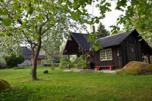 ein kleines Haus in einem Hof mit einem Baum in der Unterkunft Puise saunahouse and outdoor kitchen at Matsalu Nature Park in Puise