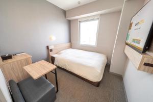a small room with a bed and a chair at Super Hotel Nagoya Shinkansenguchi in Nagoya