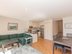 a living room with a green couch and a kitchen at Pentagon 2 65 Gippsland Street in Jindabyne