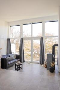 a living room with a couch and large windows at Meerhotel Großenbrode in Großenbrode