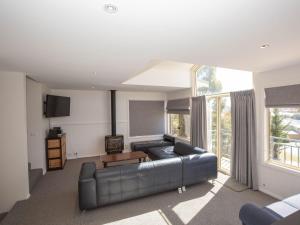 a living room with a leather couch and a large window at Torino 2 14 Nettin Circuit in Jindabyne