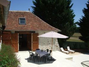 une table et des chaises avec un parasol en face d'un bâtiment dans l'établissement Gîte Abilly, 2 pièces, 4 personnes - FR-1-381-368, à Abilly-Sur-Claise