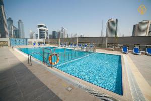 a large swimming pool with blue chairs and buildings at Splendid 1BR in Executive Bay Tower Business Bay by Deluxe Holiday Homes in Dubai