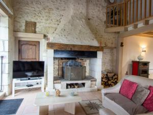 a living room with a fireplace and a tv at Maison de campagne avec piscine, proche de Périgueux – 2 chambres, BBQ, activités variées à proximité - FR-1-616-54 in Mensignac