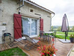 a wooden deck with a table and chairs and an umbrella at Maison de campagne avec piscine, proche de Périgueux – 2 chambres, BBQ, activités variées à proximité - FR-1-616-54 in Mensignac