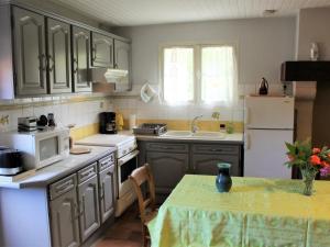 une cuisine avec des placards gris et une table avec une nappe dans l'établissement Gîte Mensignac, 3 pièces, 5 personnes - FR-1-616-40, à Mensignac