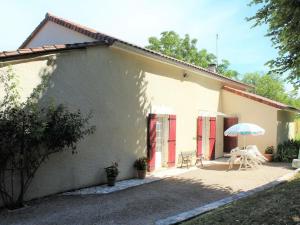 une maison blanche avec une table et un parasol dans l'établissement Gîte Mensignac, 3 pièces, 5 personnes - FR-1-616-40, à Mensignac