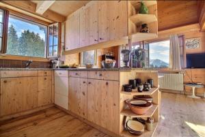 Il comprend une cuisine avec des murs en bois, du parquet et des fenêtres. dans l'établissement Chalet Soldanella 10 guests Gstaad, à Gstaad