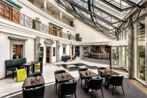 Seminaris Hotel Leipzig في لايبزيغ: فناء داخلي به طاولات وكراسي في مبنى