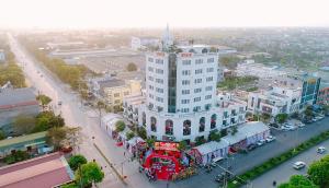 a large white building with a red bus in front of it at Khách sạn VHL Hà Nam in Phủ Lý