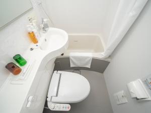 a white bathroom with a toilet and a sink at Super Hotel Nagoya Shinkansenguchi in Nagoya