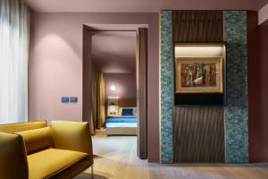 a living room with a yellow couch and a bed at Executive Spa Hotel in Fiorano Modenese