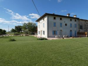 a white house with a large grass field in front of it at Agriturismo il Fontanile in Valeggio sul Mincio