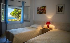 two beds in a bedroom with a window and a lamp at BIG BLUE in Rafina