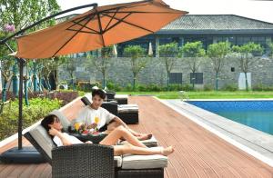 Un uomo e una donna seduti su un divano sotto un ombrello di Jinling Onejoy Hotel a Nanjing