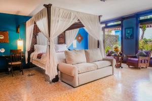 a bedroom with a canopy bed and a couch at Hotel Tugu Bali - CHSE Certified in Canggu