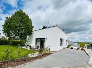 ein weißes Haus mit einem Baum und einer Auffahrt in der Unterkunft Ferienwohnung Mittelrhein Familie Lehmann in Niederburg