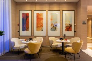 a restaurant with tables and chairs and paintings on the wall at Aemilia Hotel Bologna in Bologna