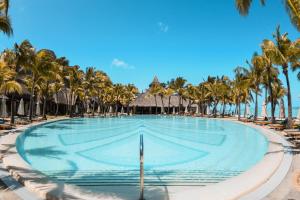 uma piscina com palmeiras e espreguiçadeiras em Paradis Beachcomber Golf Resort & Spa em Le Morne