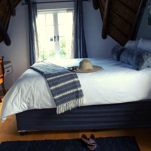 a bedroom with a bed with a hat and a window at Mond Kleine Guest House in Kleinmond