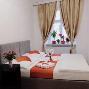a bed with orange and white sheets and a window at Lena Apartment in Prague