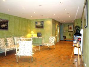 uma sala de estar com cadeiras, uma mesa e uma secretária em Hôtel La Bonne Auberge em Moustiers-Sainte-Marie