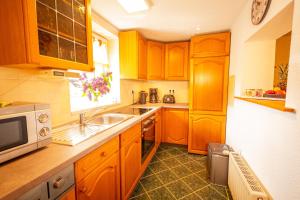 a kitchen with wooden cabinets and a sink and a microwave at Ferienhaus An der Postmeilensäule in Lübbenau