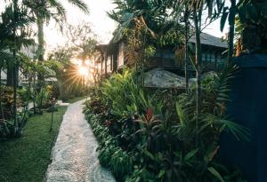a garden with a house and some plants at Hotel Tugu Bali - CHSE Certified in Canggu