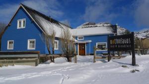 a blue house with a sign in the snow at Nothofagus Bed & Breakfast in El Chalten
