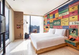 a bedroom with a large bed and a wall of signs at Hotel Indigo Kaohsiung Central Park, an IHG Hotel in Kaohsiung