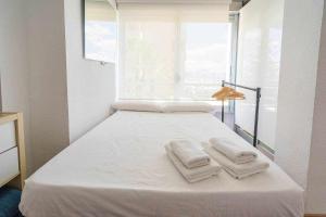 białe łóżko z ręcznikami w pokoju w obiekcie Estudio Voramar San Juan w mieście El Campello +8 zdjęć