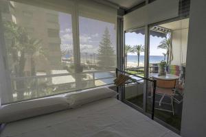 a bedroom with a bed and a view of the beach at Voramar Estudio 3Pax primera linea Playa San Juan in El Campello